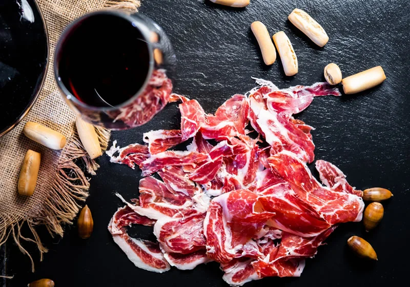 Jamón ibérico loncheado con copa de vino tinto